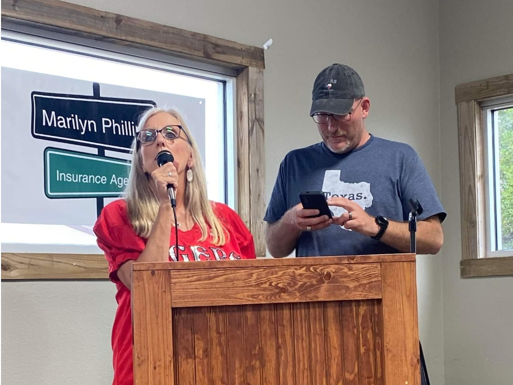 During a 2022 "Junior Tigers" youth mentoring event in Glen Rose, Texas, Dustin Mitchell wandered to the podium and stood beside organizer Tracie Hansen, as if he were part of the program. Husley said she snapped the photo because she found it so bizarre. Courtesy Sheryl Marie Hulsey