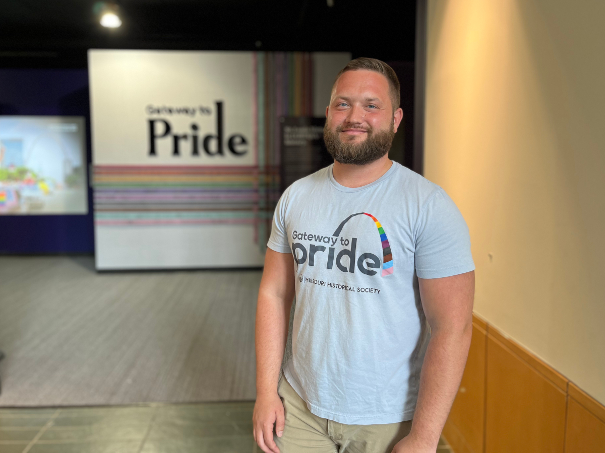 Ian Darnell stands in front of the entrance to the Gateway to Pride exhibit.